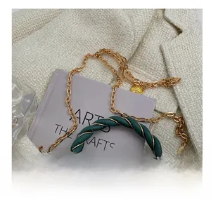 Detailed close-up of the vintage gold chain strap and embossed medallion on the green bag