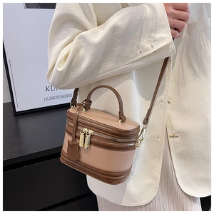 Detail of pink cylindrical leather crossbody bag with brown trim and gold hardware