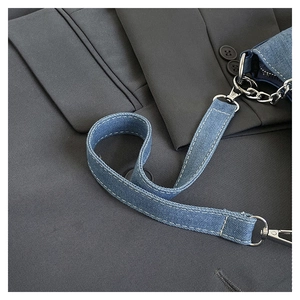 Detail view of denim shoulder strap with silver metal swivel hook and white stitching
