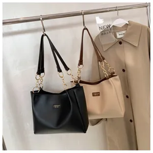 Detail of classic black and beige tote bags with chic leather and metal chain straps