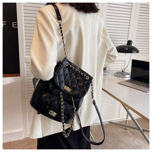 Detail of black quilted leather backpack with gold chain straps and turn-lock closure