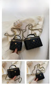 Detail of black quilted leather mini box bag with gold floral hardware and chain strap