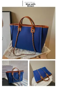 Detail view of large blue canvas bucket tote bag with brown leather trim and chain straps