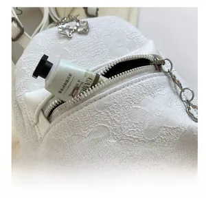 Dettaglio della borsa a tracolla in jacquard bianco con tasca frontale a zip metallica