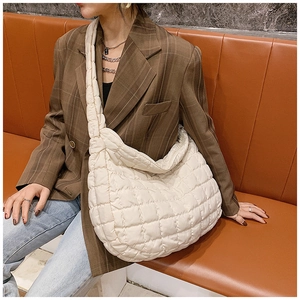 Detail of a large cream quilted hobo bag with padded texture and wide shoulder strap