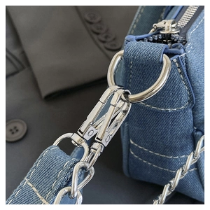 Detail of silver metal clasp and chain on blue denim bag with white contrast stitching