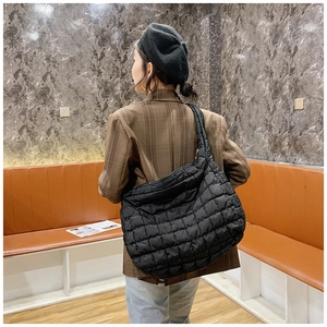 Close-up of black quilted puffer bag with crossbody strap and large capacity design