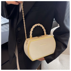 Detail of a chic cream box handbag featuring golden metal edges and a thick spiral handle
