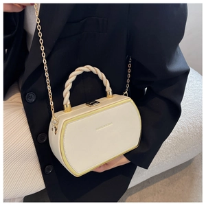 Detail of cream hexagonal handbag with gold chain strap on a black blazer