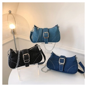 Three denim crossbody bags in black, light blue, and dark blue with large gold buckles