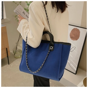 Detailed view of deep blue felt tote bag with chain strap and black handles