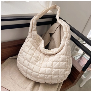 Close-up of beige quilted tote bag on wooden bench showing texture and premium craftsmanship