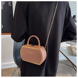 Close-up of pink hexagonal handbag with gold chain strap and woven top handle