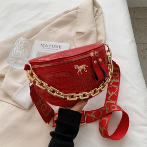 Red crocodile pattern fanny pack with chunky gold chain and horse logo on beige suit