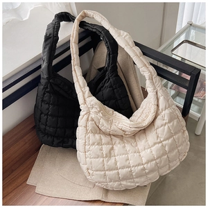 Quilted puffer tote bags in black and cream white colors displayed on a bench