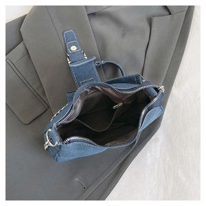 Detail view of denim crossbody bag interior showing brown lining and zipper pocket