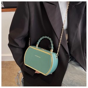 Detail of green box bag with gold metal trim and fashion text worn by model in suit
