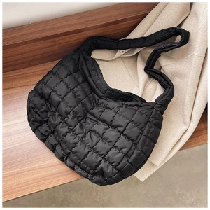 Close-up of black quilted puffer tote bag with square stitching and soft nylon texture