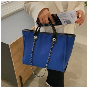 Detail of Klein Blue felt tote bag featuring black leather handles and silver chain link