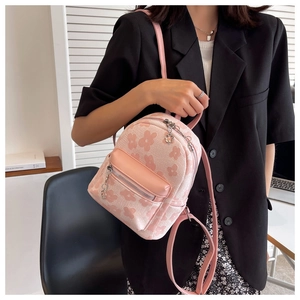 Dettaglio di mini zaino in tela rosa a fiori con tiranti della zip a forma di fiore