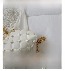 Détail d'un sac de soirée blanc matelassé avec perles et cadre en métal doré gravé
