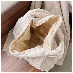 Close-up of quilted beige tote bag showing smooth zipper and spacious inner compartment