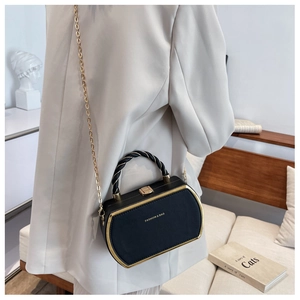 Detail of elegant black box bag with gold metal trim and chain strap shown on model