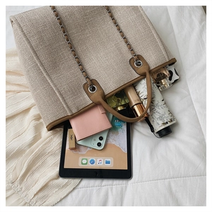 Detail view of large woven tote bag showing internal storage for tablet and cosmetics