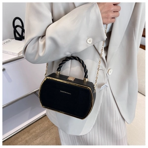 Close-up of black hexagonal chain crossbody bag with golden frame and twisted handle