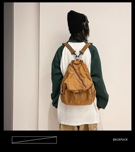 Brown washed canvas backpack shown in a lifestyle view on a male model with streetwear style