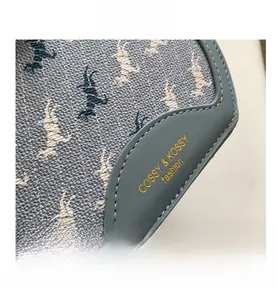Close-up of blue textured fabric with horse print and gold brand logo on the handbag