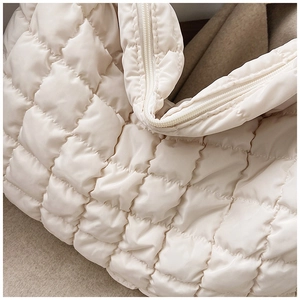 Detailed view of quilted down tote bag fabric texture with smooth zipper closure