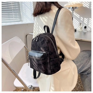 Primo piano di un mini zaino jacquard nero indossato da una modella con luce soffusa