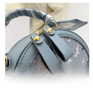 Detail showing smooth double metal zippers and blue floral fabric on a round handbag