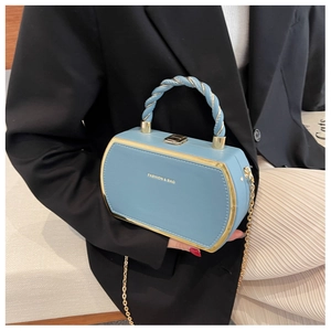 Detail of blue hexagonal leather handbag with gold trim and twisted woven handle