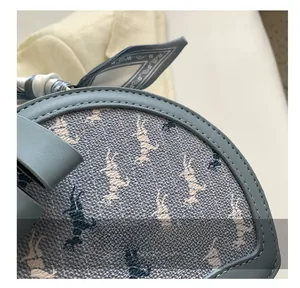 Close-up of precise stitching on blue round crossbody bag with printed horse patterns