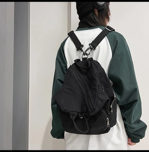 Detail of adjustable nylon straps and metal hooks on a black washed canvas backpack