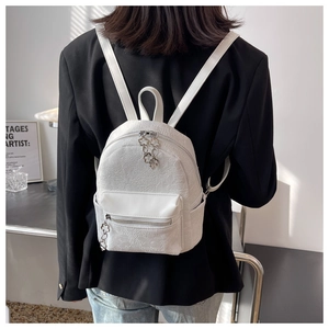 Dettaglio mini zaino bianco con motivi floreali a rilievo e tiretti a forma di fiore