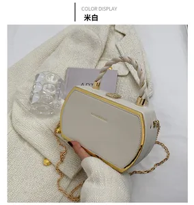 Detail view of beige structured handbag with braided handle and gold chain strap