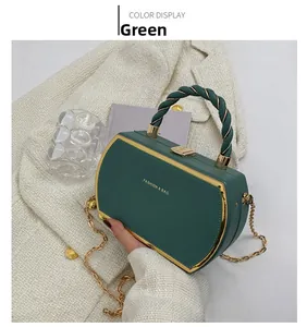 Detail of green trapezoid handbag featuring gold metal trim and twisted handle texture