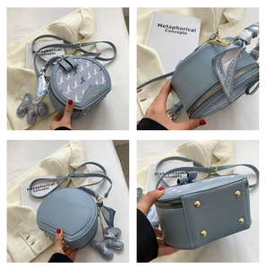 Detail view of light blue round bag featuring horse print, silk scarf handle and metal feet