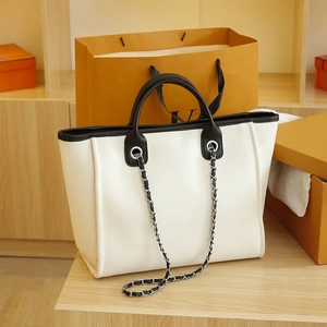 Minimalist large white canvas tote bag with black leather trim and metal chain strap