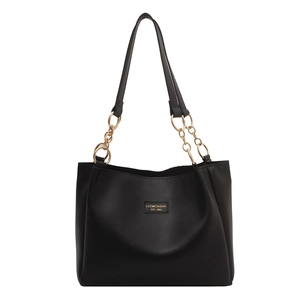 Black vegan leather tote bag with gold chain straps and logo print on white background