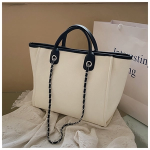 Detail of canvas tote bag with black leather trim and silver metal chain strap
