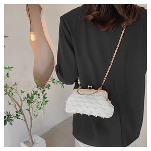 Détail d'un sac de soirée blanc matelassé avec perles et chaîne dorée sur mannequin