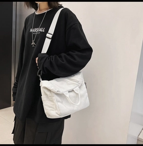 Adjustable shoulder strap and side pocket detail of a large white canvas crossbody bag