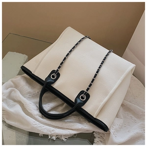 Detail of canvas tote bag with black leather trim and silver metal chain strap