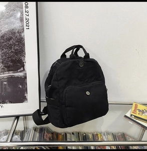Detail of black canvas backpack showing magnetic buckle pocket and sturdy handle strap