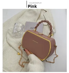 Detail of pink PU leather heart-shaped handbag with gold metal trim and woven handle