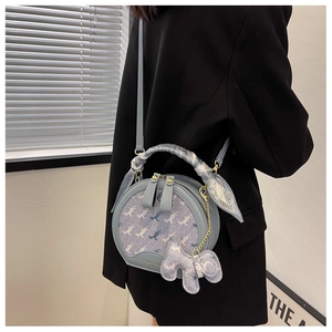 Detail view of a light blue round handbag with horse jacquard and silk scarf handle